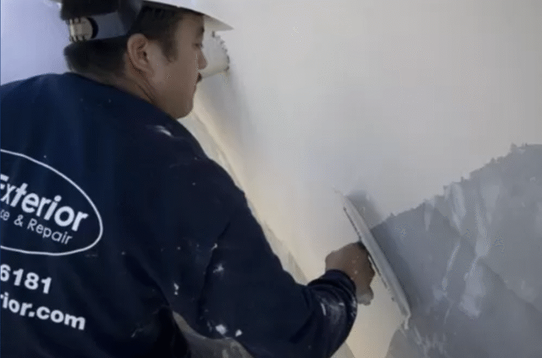 A US Exterior crew member applies a coating to a building